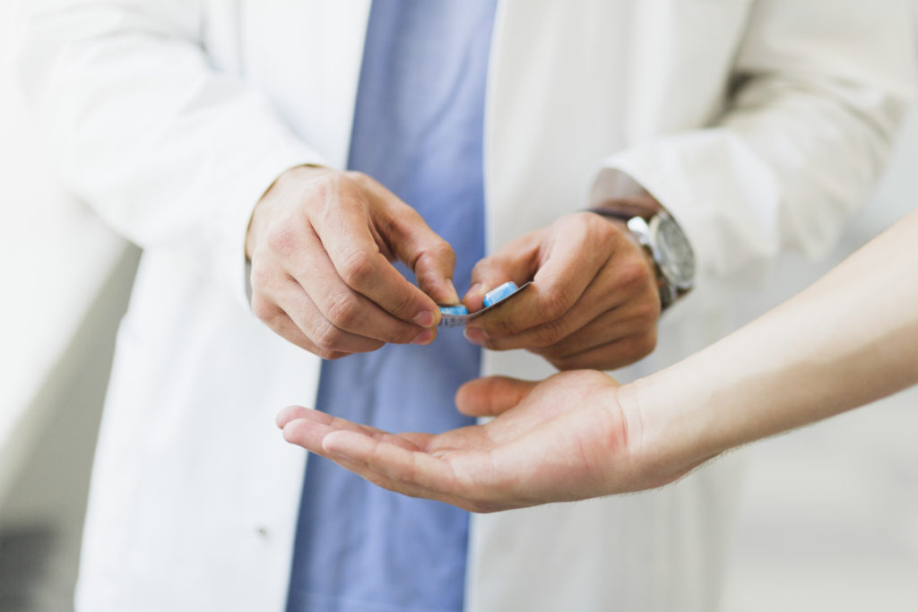 Doctor giving patient pills from a blister package.