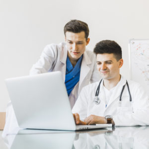 Two doctors working together on a laptop computer.
