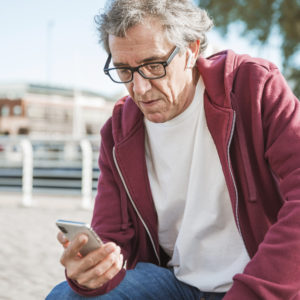 Elderly man checking his mobile phone for appointment times.