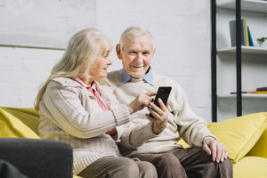 Elderly couple scheduling a doctor's office visit on a cellphone.